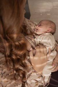 "Moeder knuffelt slapende pasgeboren baby in armen – warme newbornshoot binnen, liefdevolle moeder-kind fotografie, vastgelegd door newbornfotograaf ByIrisvdZwan in 's Gravenzande, Westland, regio Den Haag.