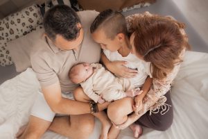 "Gezinsfotoshoot met pasgeboren baby, ouders en grote broer samen op bed – liefdevolle newborn en familie fotografie"