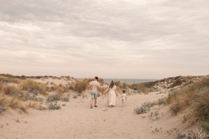 “Gezinsfotoshoot in de duinen van ’s-Gravenzande, Westland – liefdevol gezin dat samen richting zee wandelt, vastgelegd door ByIrisvdZwan in de natuur van de regio Den Haag.”