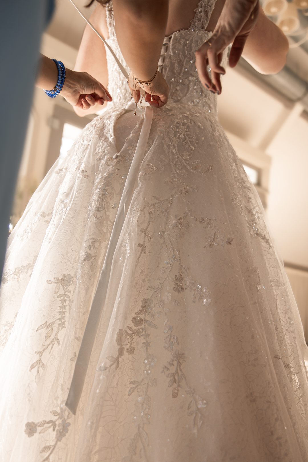 Detailfoto van de bruid die haar schoenen aandoet onder haar elegante trouwjurk, tijdens bruiloft, vastgelegd door ByIris vanderZwan, bruidsfotograaf in Westland, ’s-Gravenzande regio Den Haag voor oog voor kleine momenten tijdens bruiloften.