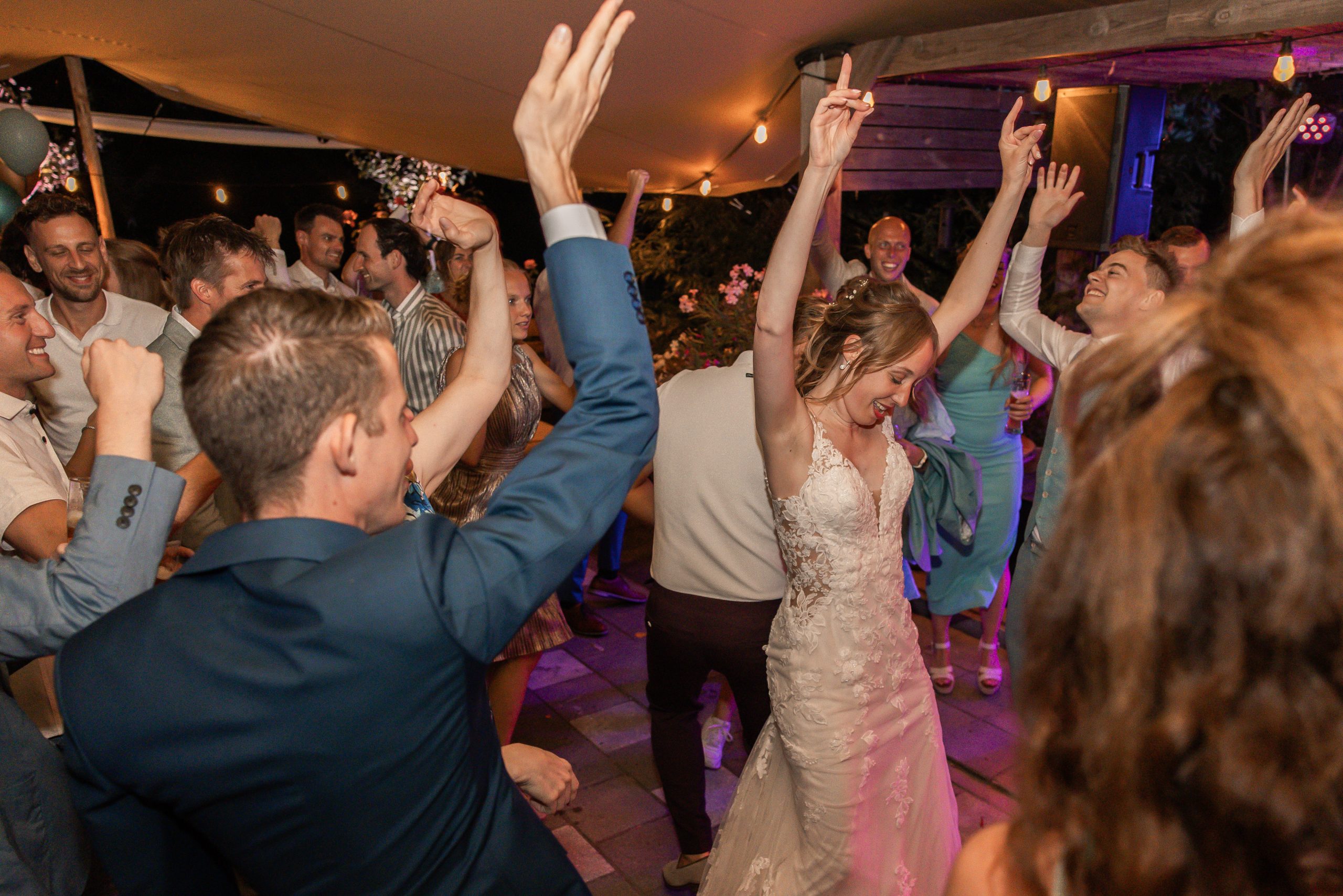 Bruiloftsgasten dansen op de dansvloer met de bruid tijdens avondfeest, spontane trouwreportage door ByIrisvdZwan, bruidsfotograaf in Westland, ’s-Gravenzande en regio Den Haag.