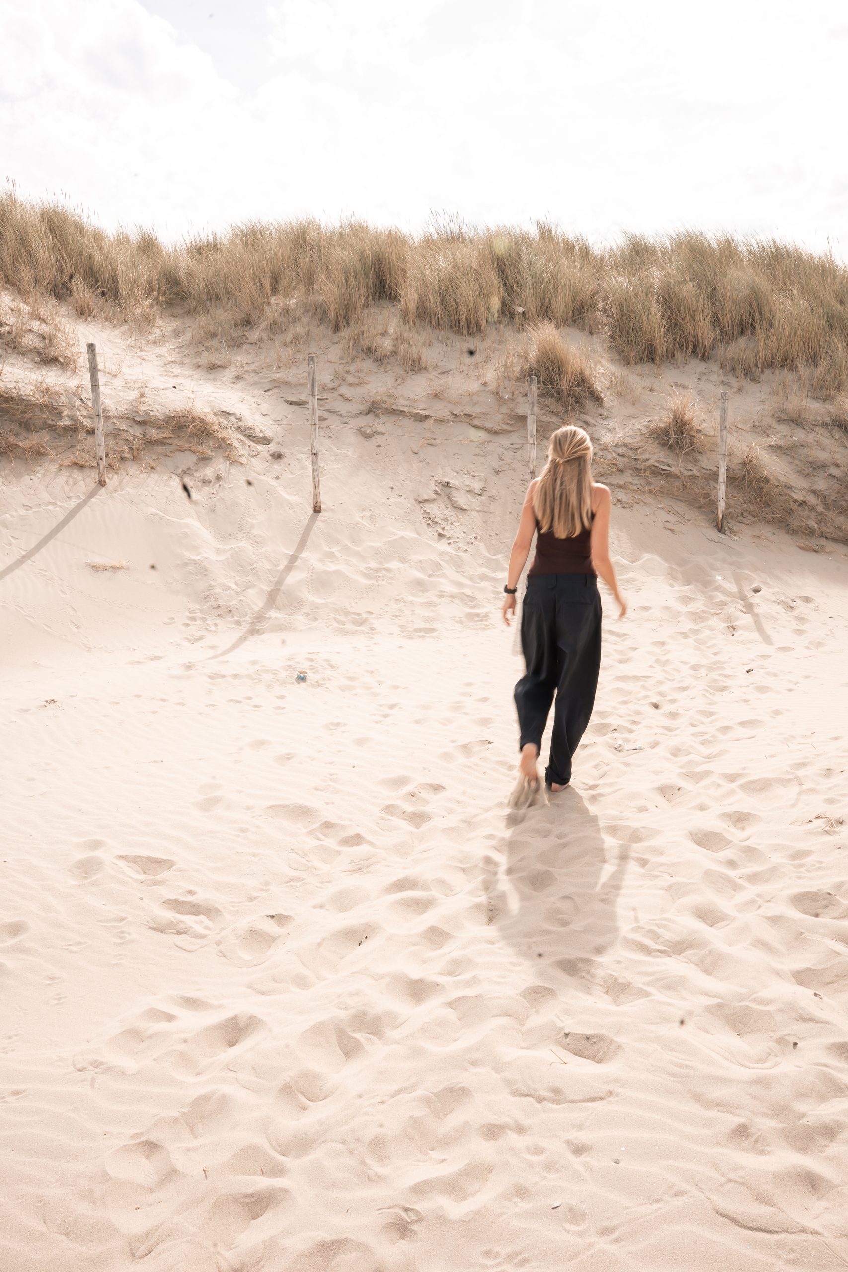 Vrouwelijke ondernemer loopt door de duinen bij zonsondergang, symbool voor vrijheid, rust en ondernemen op eigen voorwaarden, Westland, ’s-Gravenzande, regio Den Haag