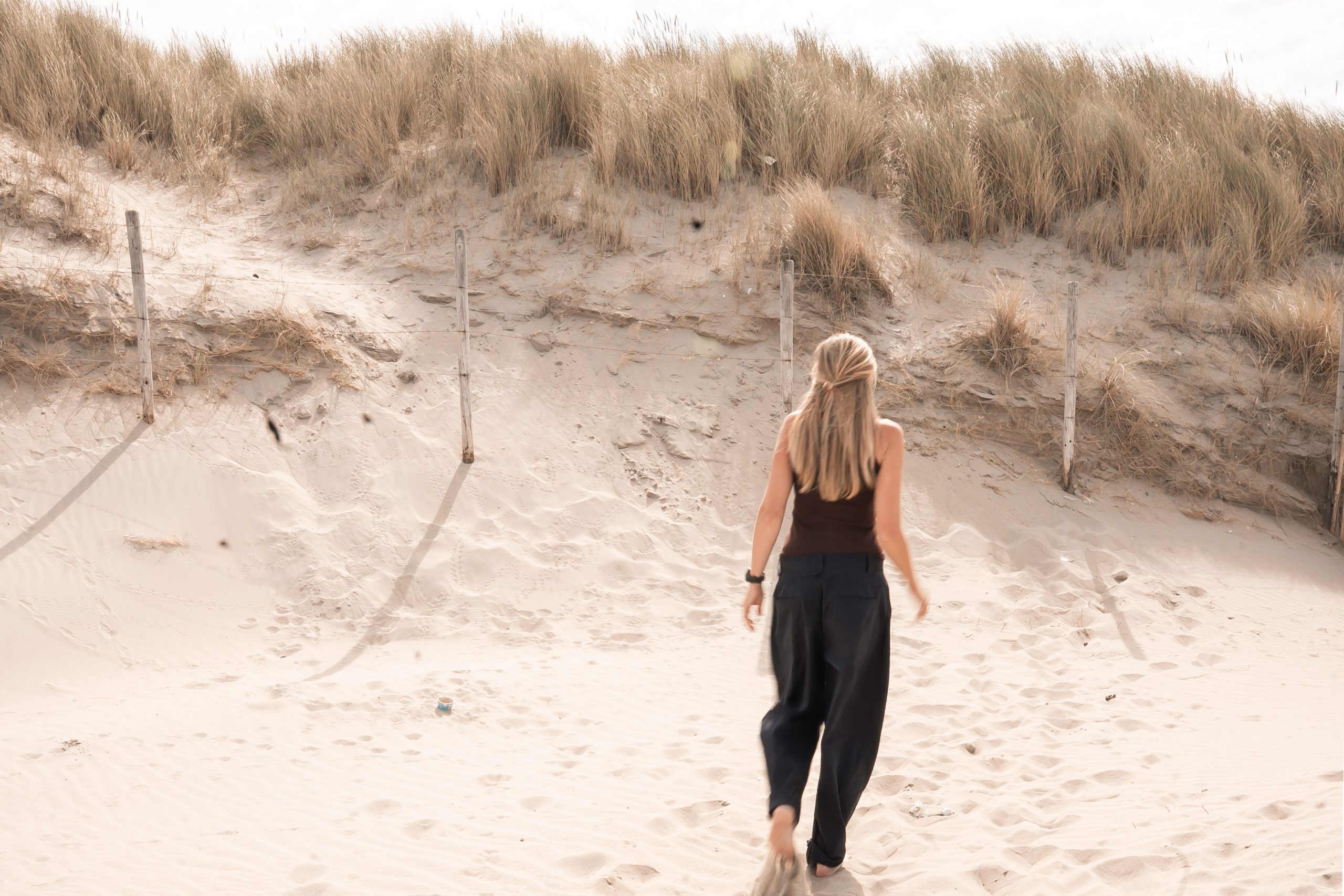 Vrouwelijke ondernemer loopt door de duinen bij zonsondergang, symbool voor vrijheid, rust en ondernemen op eigen voorwaarden, Westland, ’s-Gravenzande, regio Den Haag