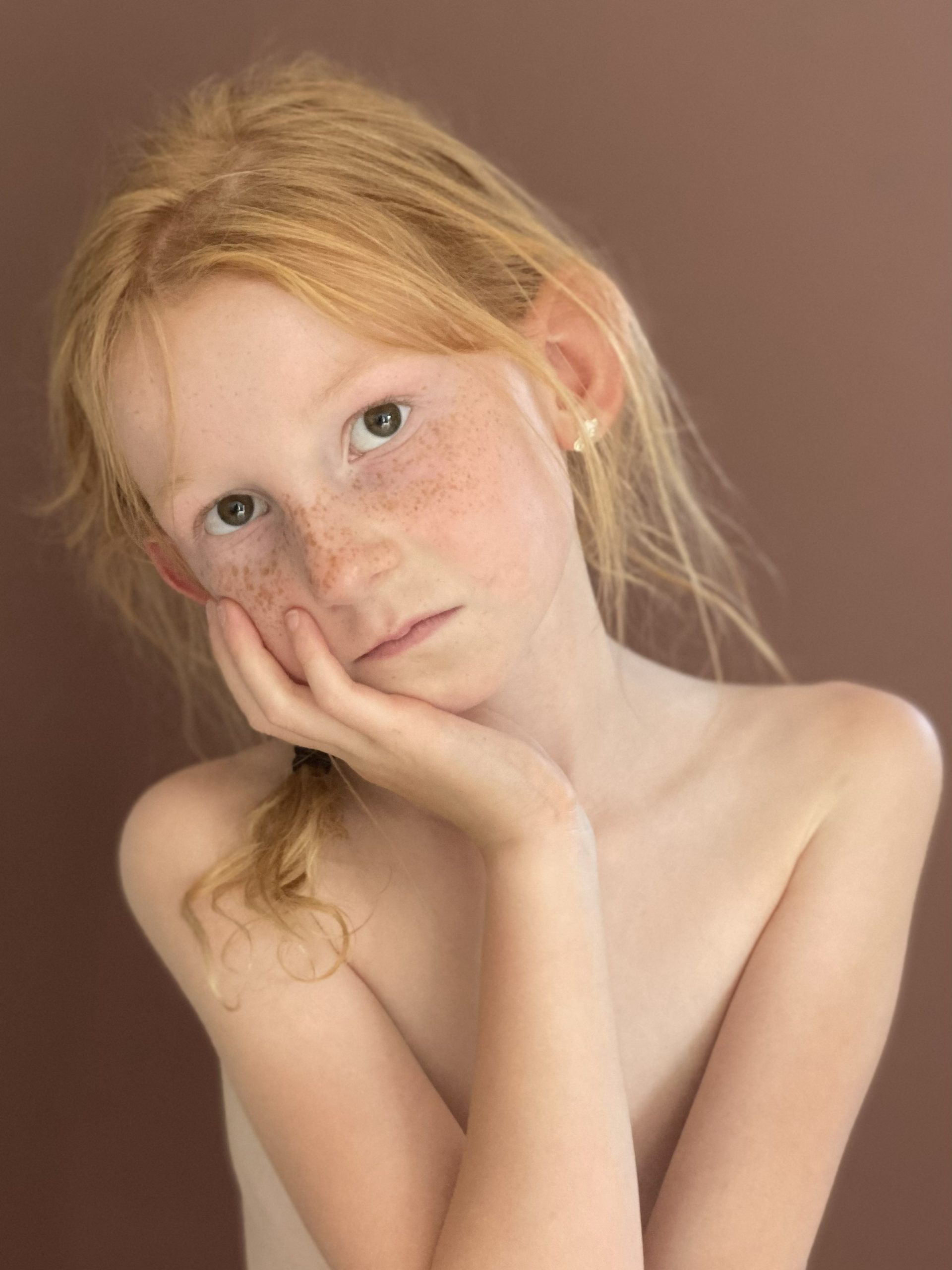 Close-up portret van meisje met sproetjes en lichte ogen, zachte blik en warm licht, vastgelegd tijdens professionele fotoshoot in ’s-Gravenzande, Westland, regio Den Haag, tijdloze en natuurlijke portretfotografie