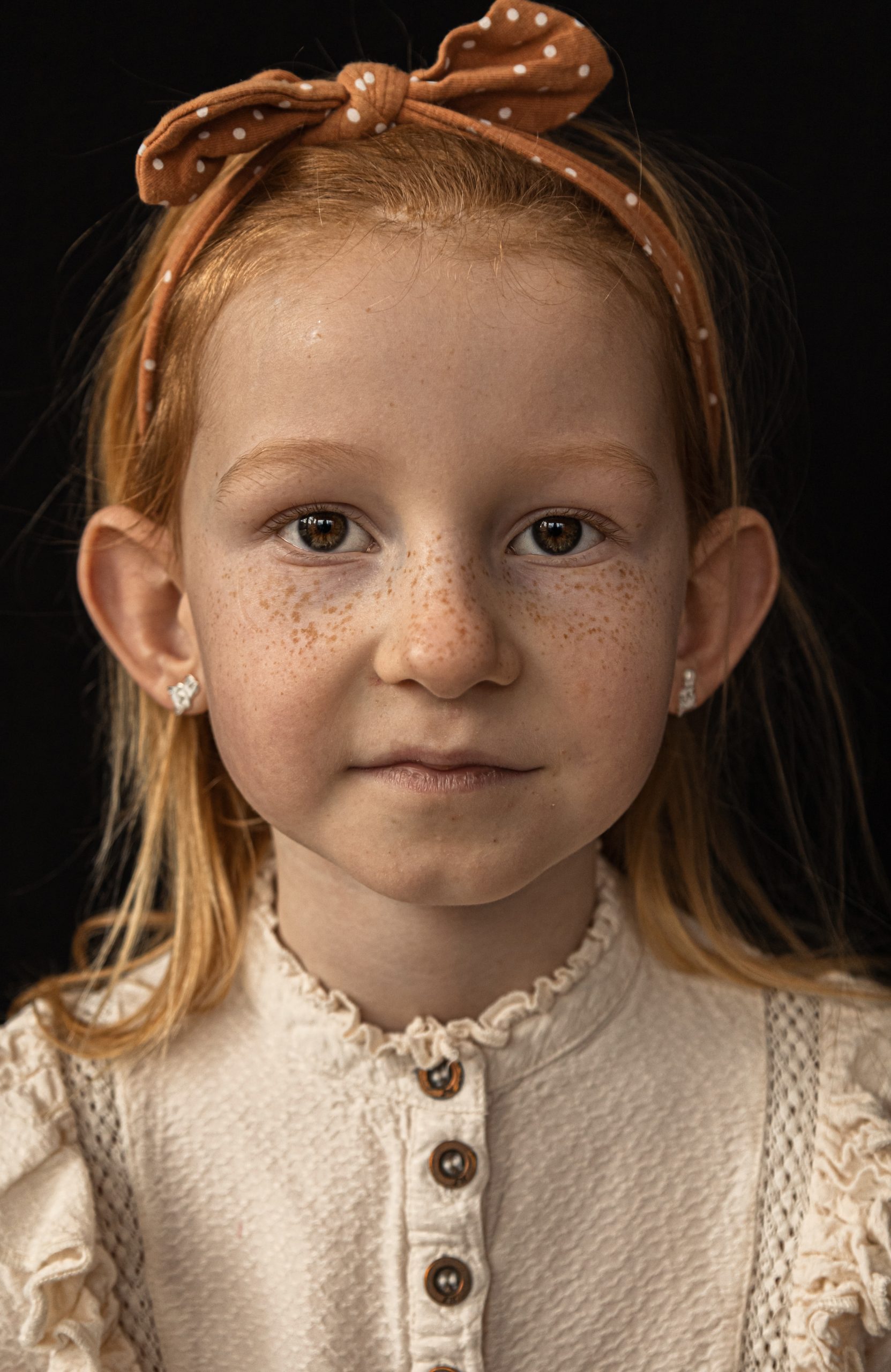 Close-up portret van meisje met sproetjes en lichte ogen, zachte blik en warm licht, vastgelegd tijdens professionele fotoshoot in ’s-Gravenzande, Westland, regio Den Haag, tijdloze en natuurlijke portretfotografie
