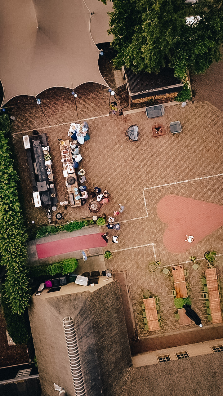 Dronefoto van een landelijke trouwlocatie met ceremonie-opstelling, stretchtent en buitenbar in het Westland, regio Den Haag.