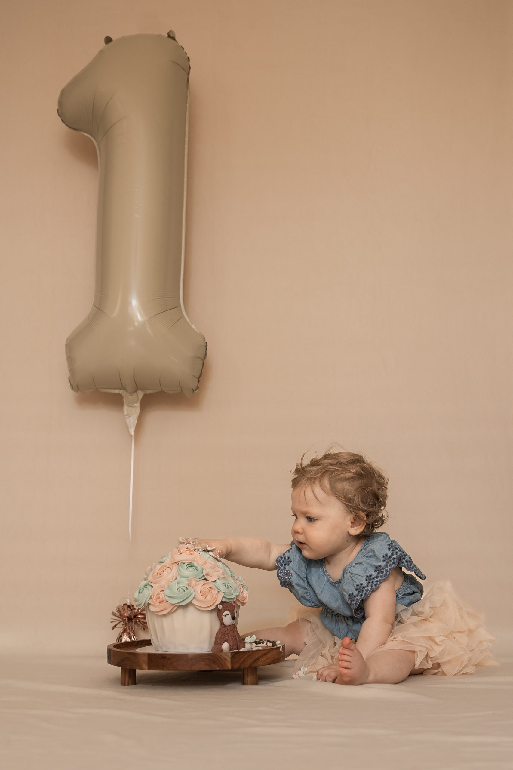 Cakesmash in ’s-Gravenzande en Westland van een vrolijk kind tijdens een eerste verjaardagsshoot met taart en cijferballon, gemaakt door ByIrisvdZwan