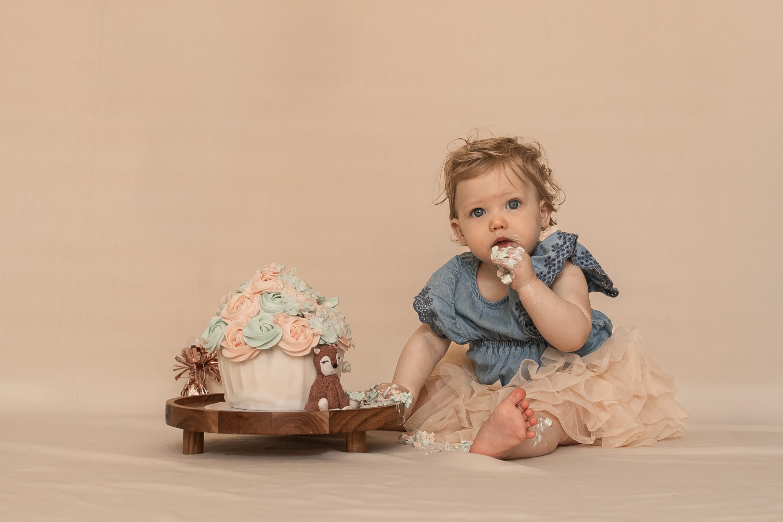 Cakesmesh in ’s-Gravenzande en Westland van een vrolijk kind tijdens een eerste verjaardagsshoot met taart en cijferballon in studio van ByIrisvdZwan, trouwfotograaf.